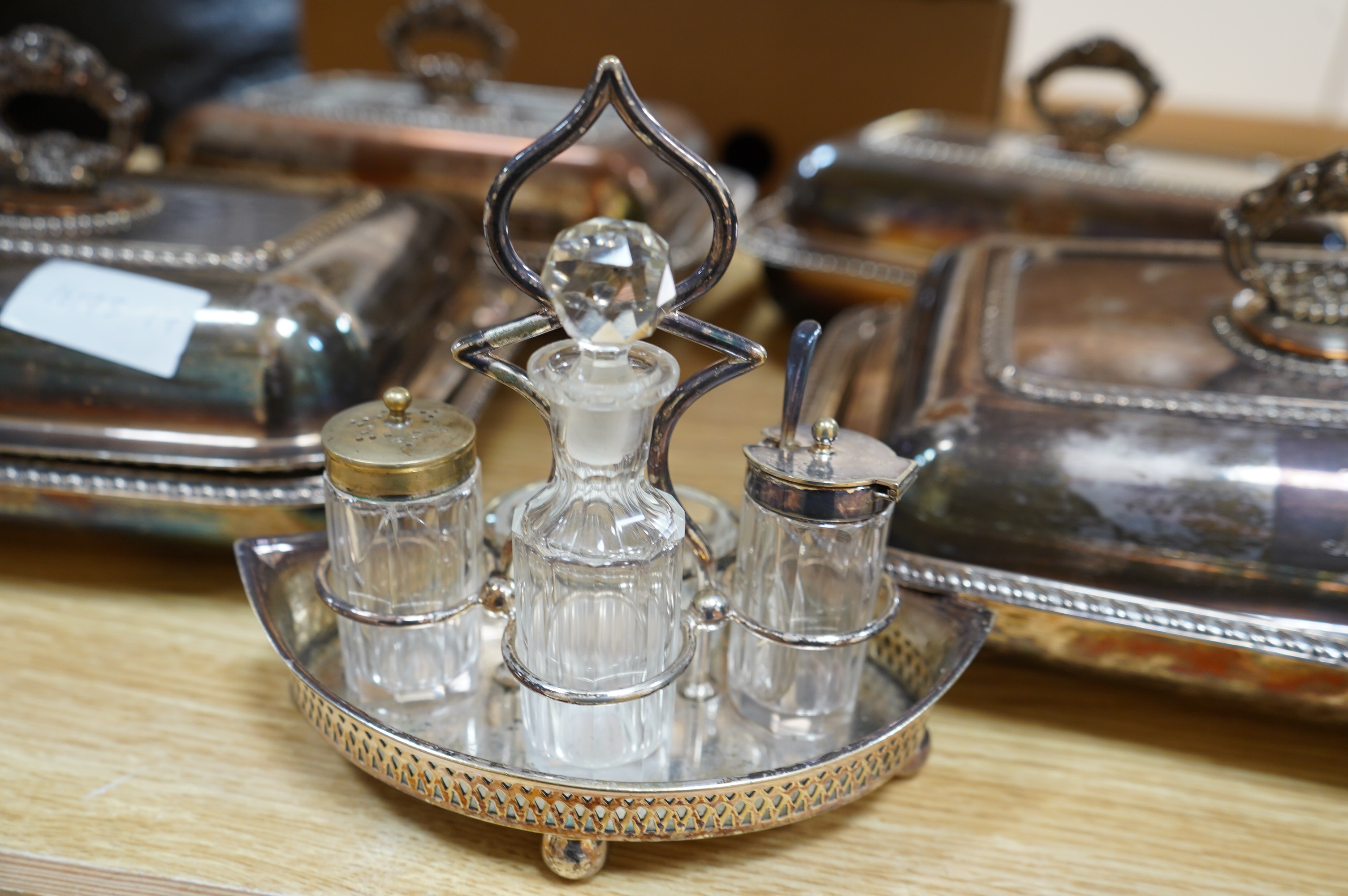 A set of four silver plated entrée dishes and covers and a plated four piece condiment stand, largest entree dish 22cm wide, 29cm long. Condition - plate worn